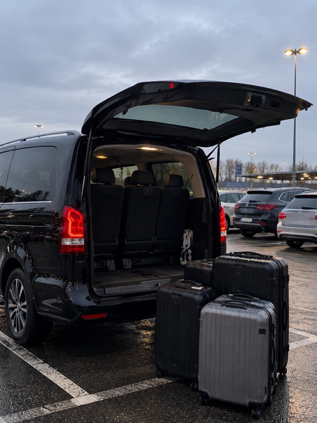 Navette Flex Airpark, coffre ouvert, bagages posés à l'arrière sur le parking
